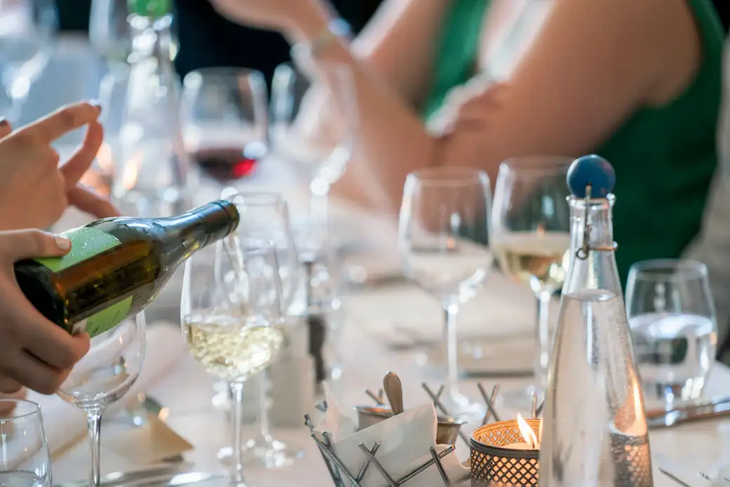 White wine being poured into a glass at a set table