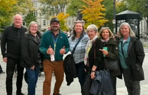 Seven members of the group smiling together in a Quebec City square under autumn trees